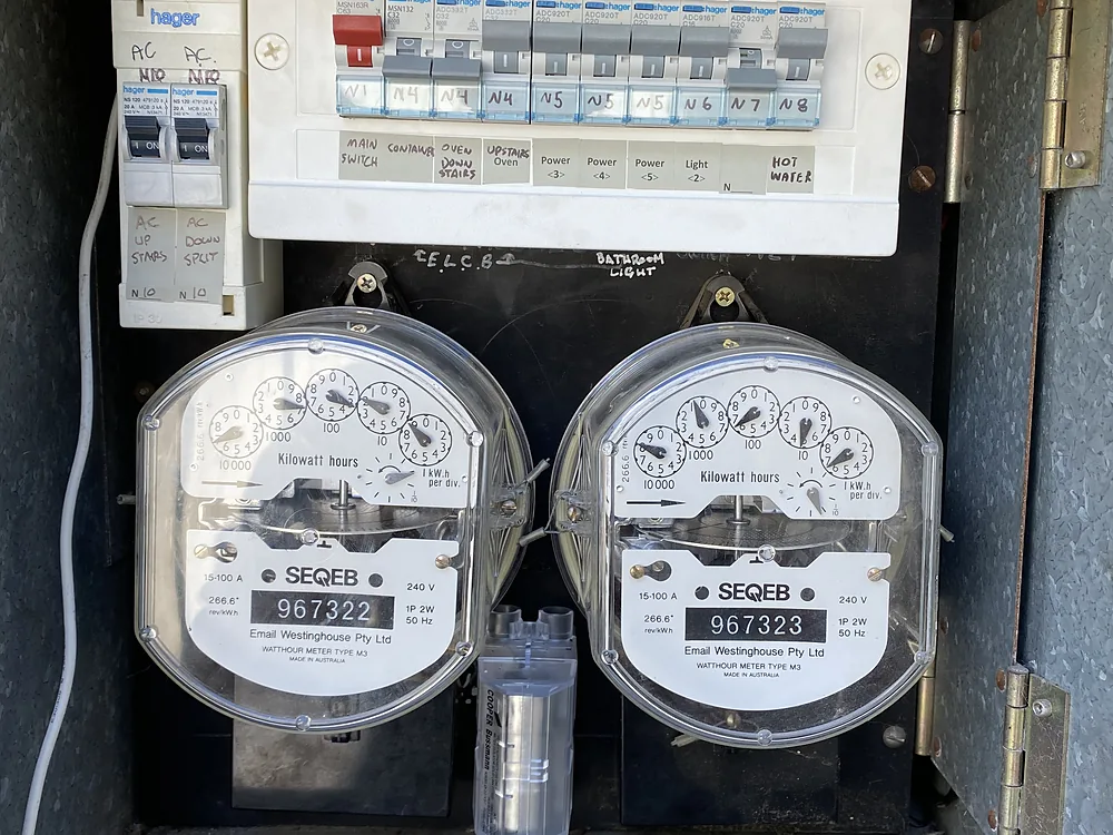 A new modular switchboard with safety switches fitted above two old analogue meters in a timber meter box
